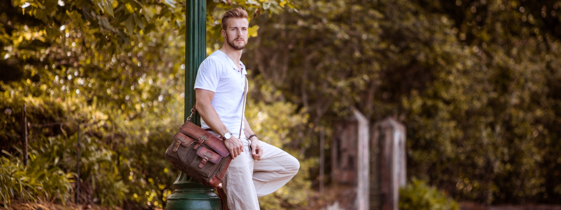 Männliches Modell steht mit einer Leder Handtasche von Drakensberg an einer Strasse